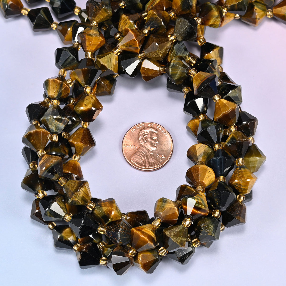 Close-up of 10mm Iron Tiger Eye faceted bicone beads coiled into a circle, highlighting the deep brown color with golden banding.