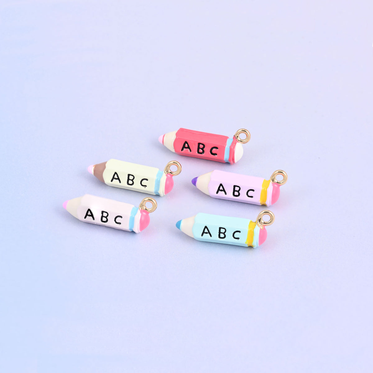 Five pencil charms in a group, one in each color with the ABC face turned up.