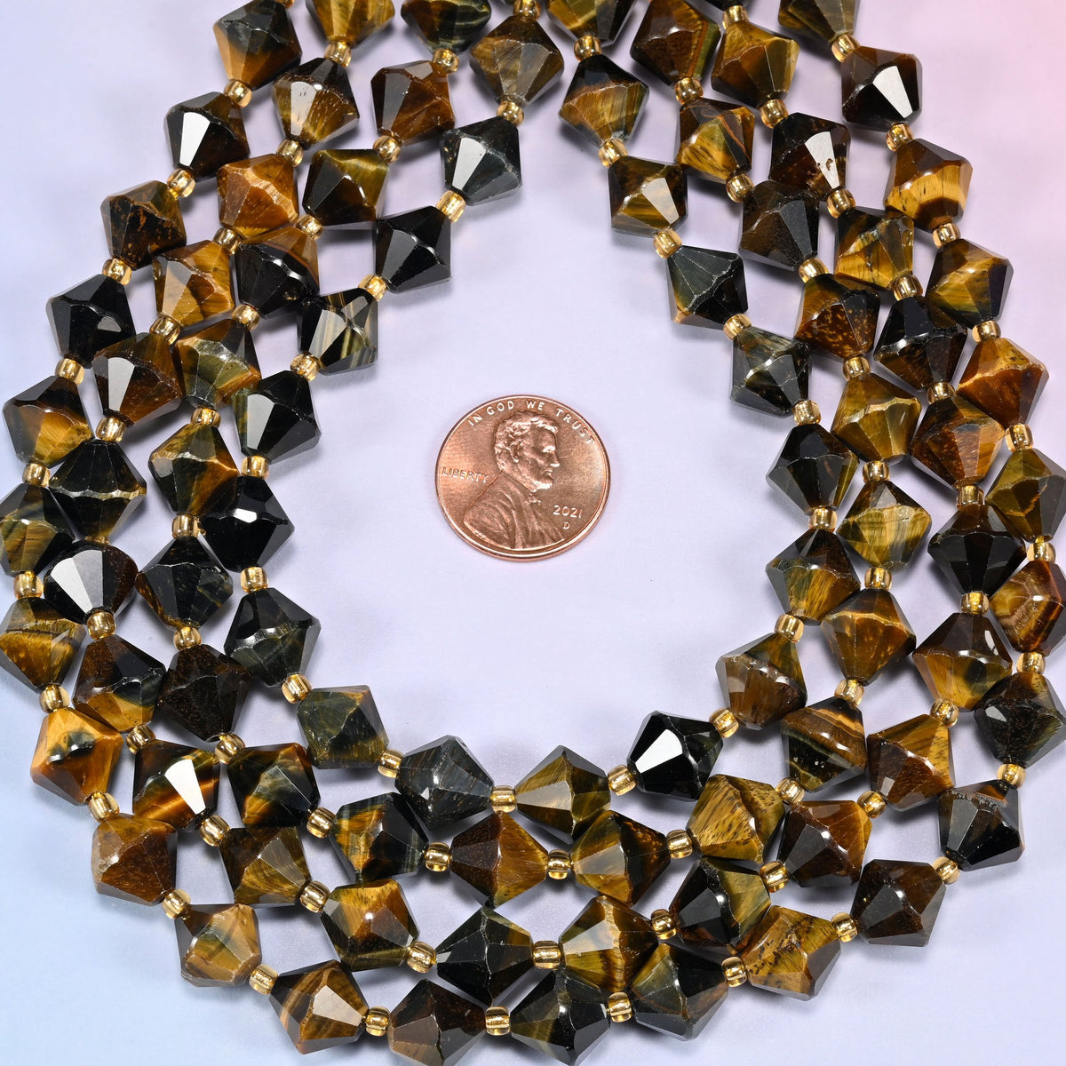 Close-up of 10mm Iron Tiger Eye faceted bicone beads coiled into a circle, showing the faceted bicone shape and banded coloring.