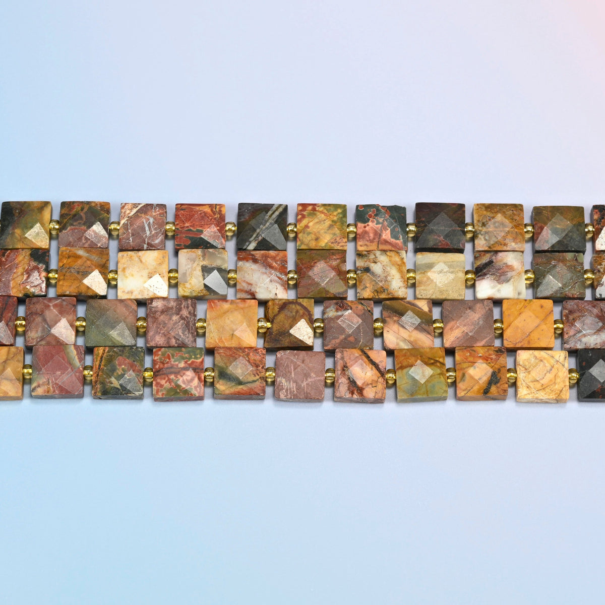 Several strands of natural red howlite faceted flat square beads laid in straight rows