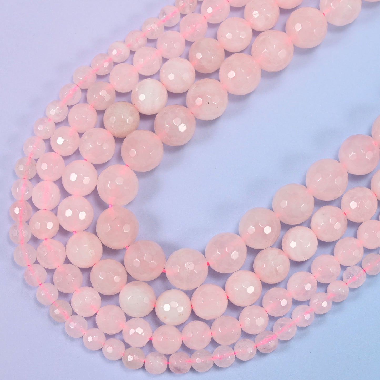 Macro detail of pink rose quartz bead surface, highlighting the faceted texture and shine.