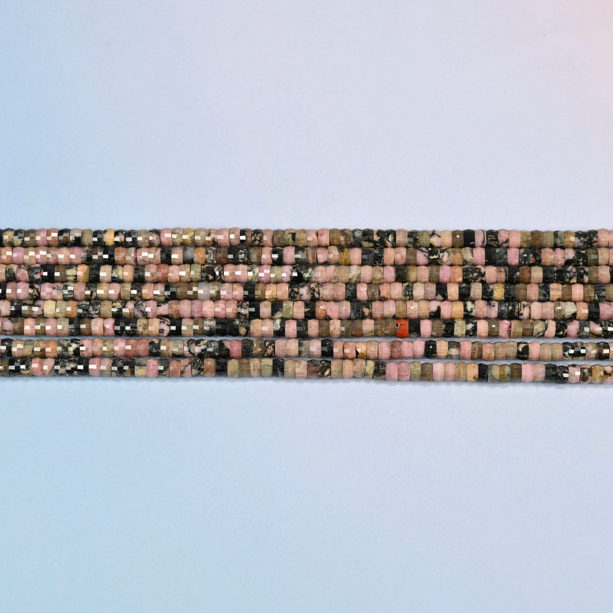 Several strands of rhodonite faceted heishi disc beads laid in straight rows
