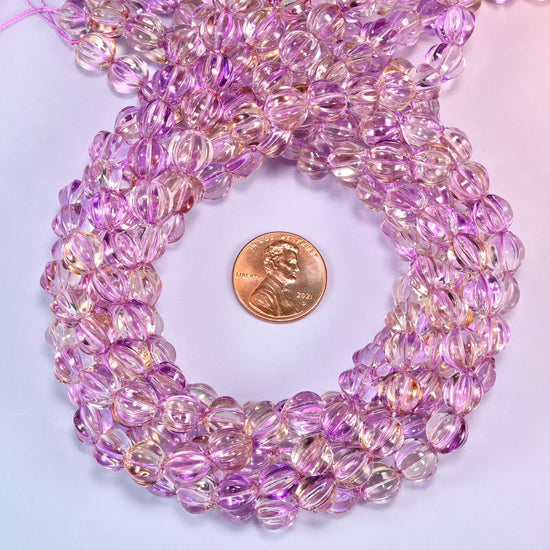 Clear purple gold pumpkin glass beads coiled into a tight spiral, the strand end trailing off the top corner.
