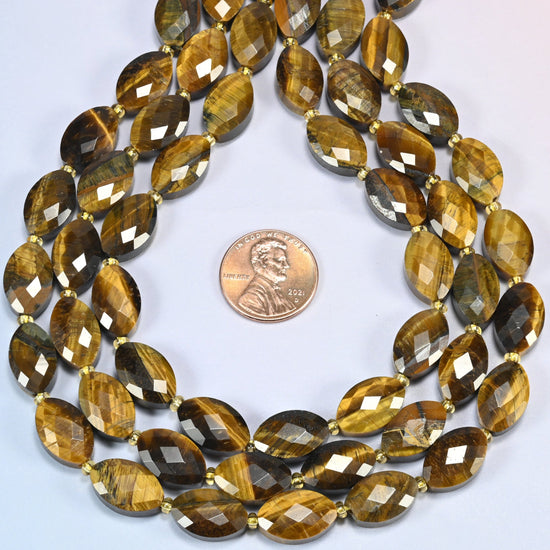 Tiger eye faceted flat oval strands formed into a teardrop loop around a US penny for scale