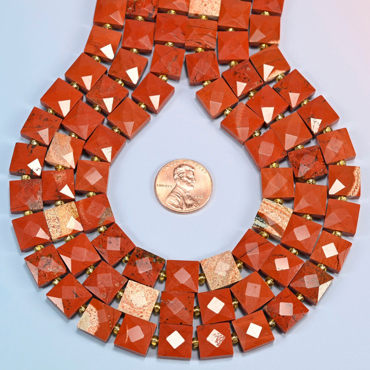 Natural flower red jasper faceted flat square strands formed into a teardrop loop around a US penny for scale
