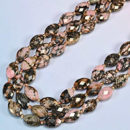 Rhodonite faceted flat oval beads in several strands curved into a wide U, dusty pink stone with black veins