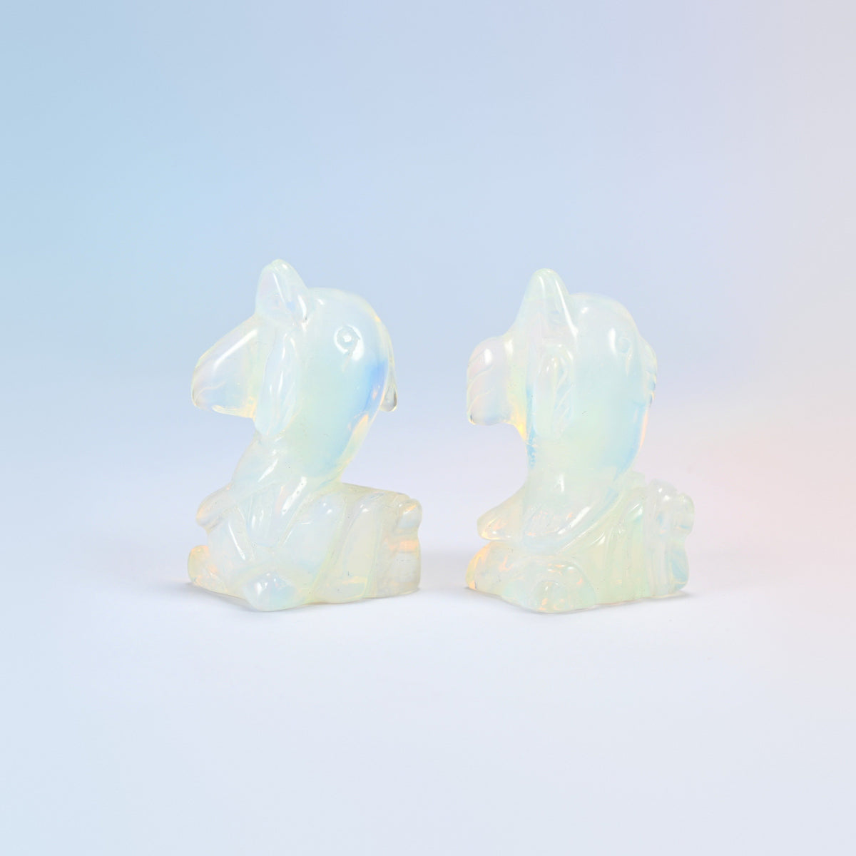 Two opalite dolphin on wave carvings facing each other