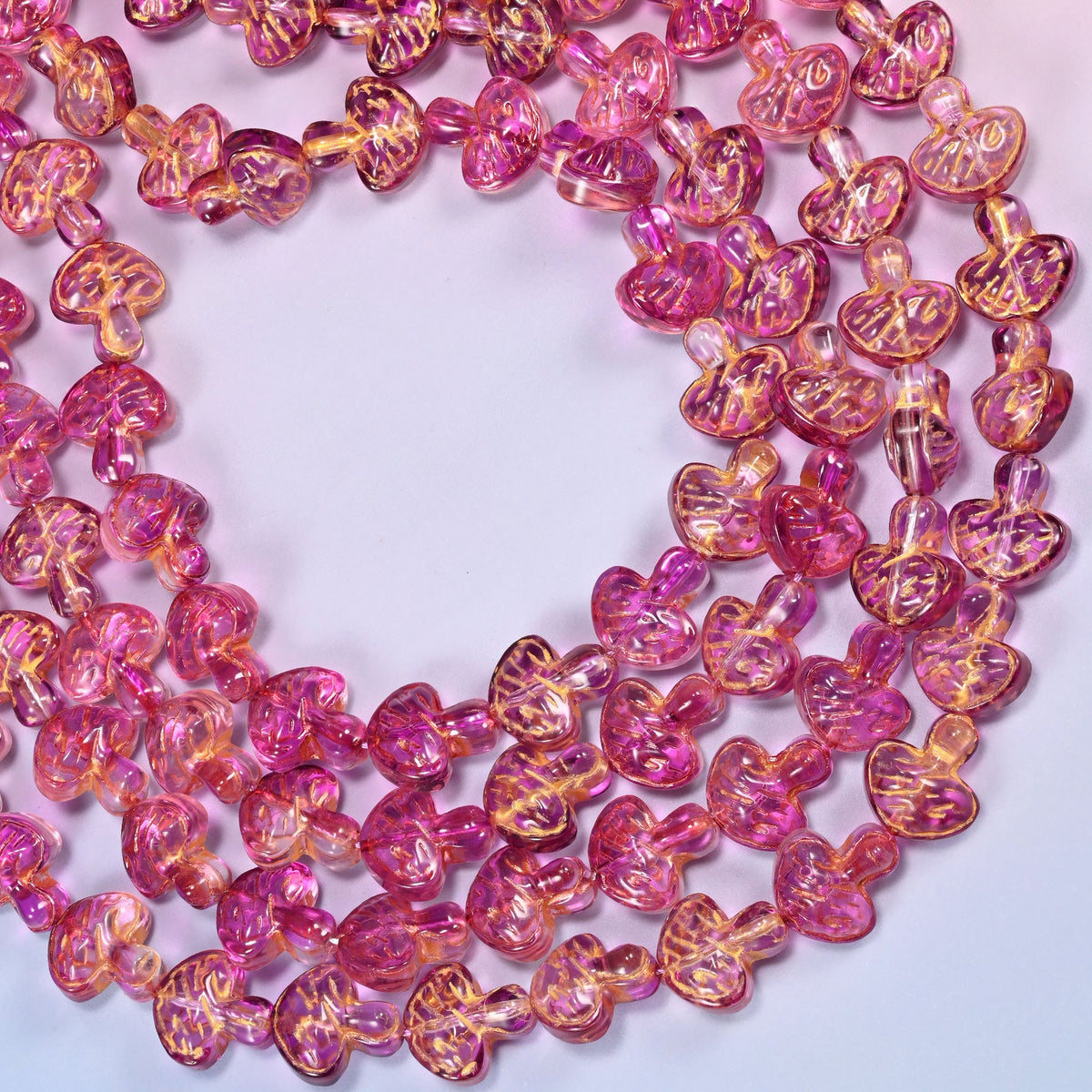 Pink gold flat mushroom glass beads looped into one wide open ring, the strands running off both sides of the frame.
