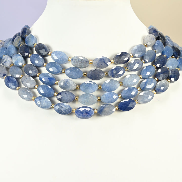 Blue aventurine faceted flat oval strands arranged as a layered collar on a white display bust, blue beads across the neck
