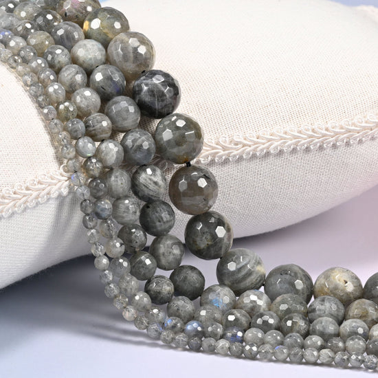 Gray Labradorite faceted round beads draped in a soft curve, silver gray through charcoal with blue flash lifting off the cut planes