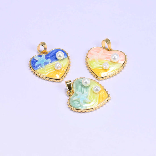 Enamel Heart Pendants shown tilted on their sides, blue and pink above and green below, so the gold plated bail and the depth of the enamel are visible.