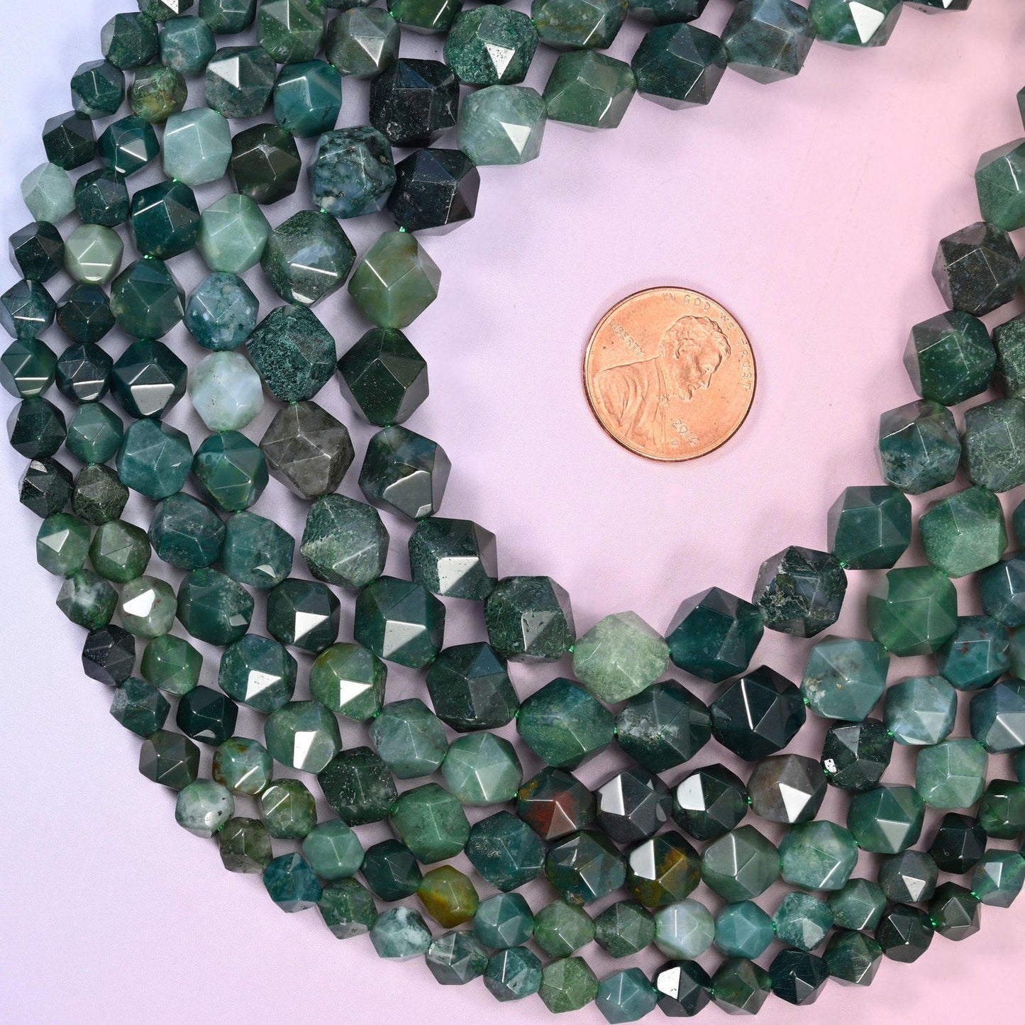 Moss Agate diamond star cut beads coiled around a US penny for size reference, centre drilled