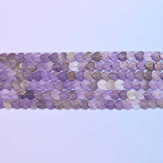 Angled view of purple and lavender amethyst flat heart-shaped beads highlighting the flat heart-shaped cut and 6mm matte beads, 15 inch strand
