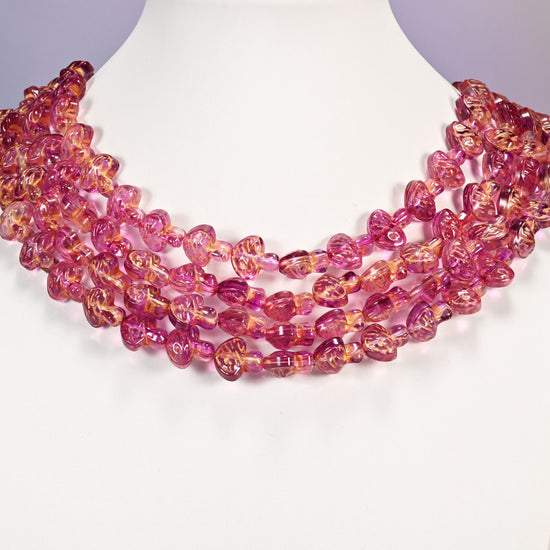 Pink gold flat mushroom glass beads arranged as a layered collar, the 15 inch strands curving in even rows.