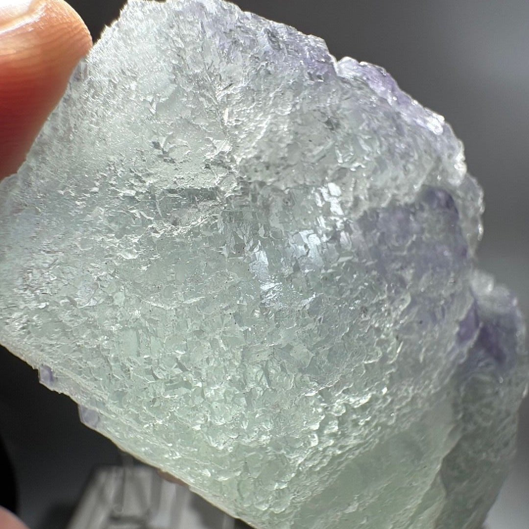 The fluorite catching daylight, its pale green body turning translucent along the thinner edges