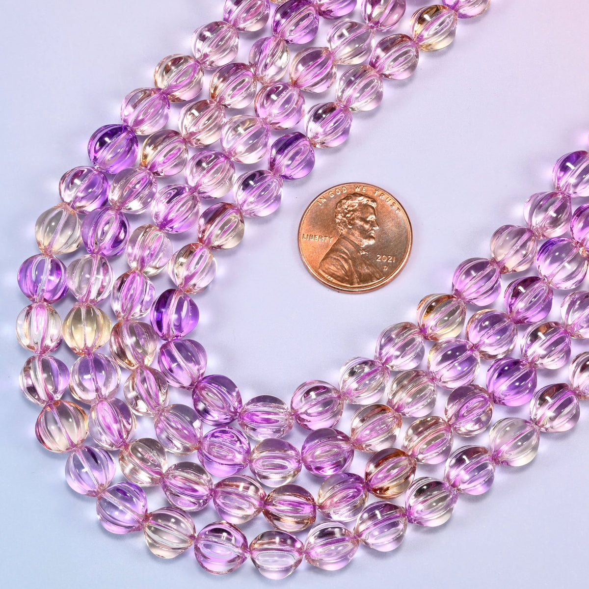Clear purple gold pumpkin glass beads laid in a wide shallow bend, the violet running deeper down the grooves and clearing at the high points.