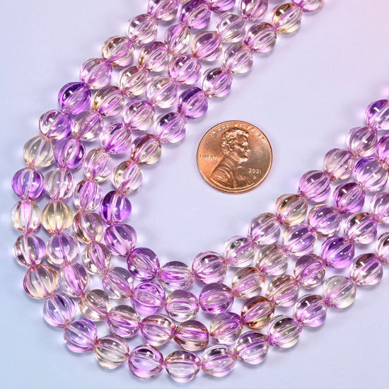 Clear purple gold pumpkin glass beads laid in a wide shallow bend, the violet running deeper down the grooves and clearing at the high points.