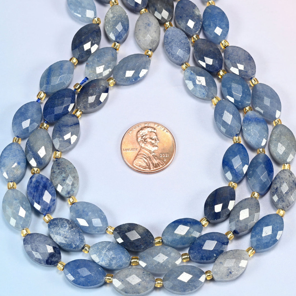 Blue aventurine faceted flat oval strands formed into a teardrop loop around a US penny for scale
