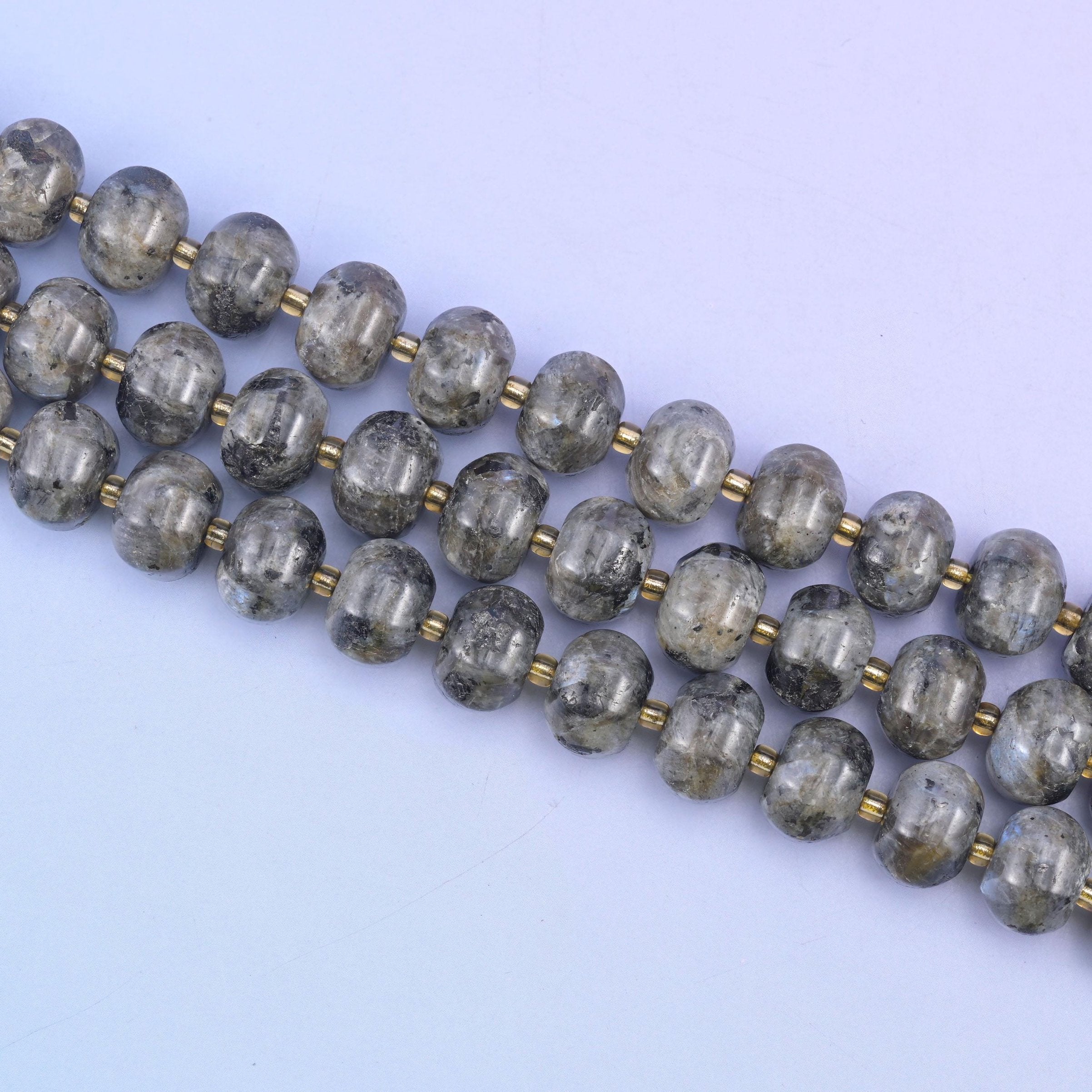 Angled run of 12x8mm pumpkin rondelles across pale lilac, carved grooves catching the light