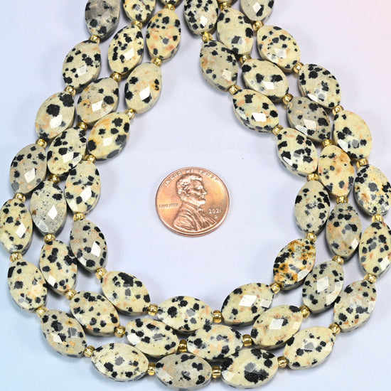 Dalmatian jasper faceted flat oval strands formed into a teardrop loop around a US penny for scale