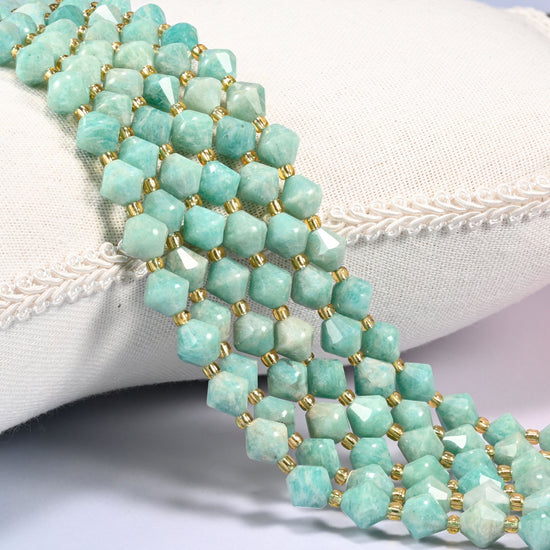 Green Amazonite faceted bicone beads 8mm with gold-tone spacers, strand draped over a woven cushion trim