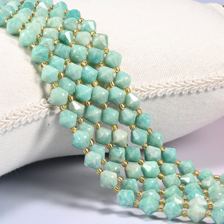 Green Amazonite faceted bicone beads 8mm with gold-tone spacers, strand draped over a woven cushion trim
