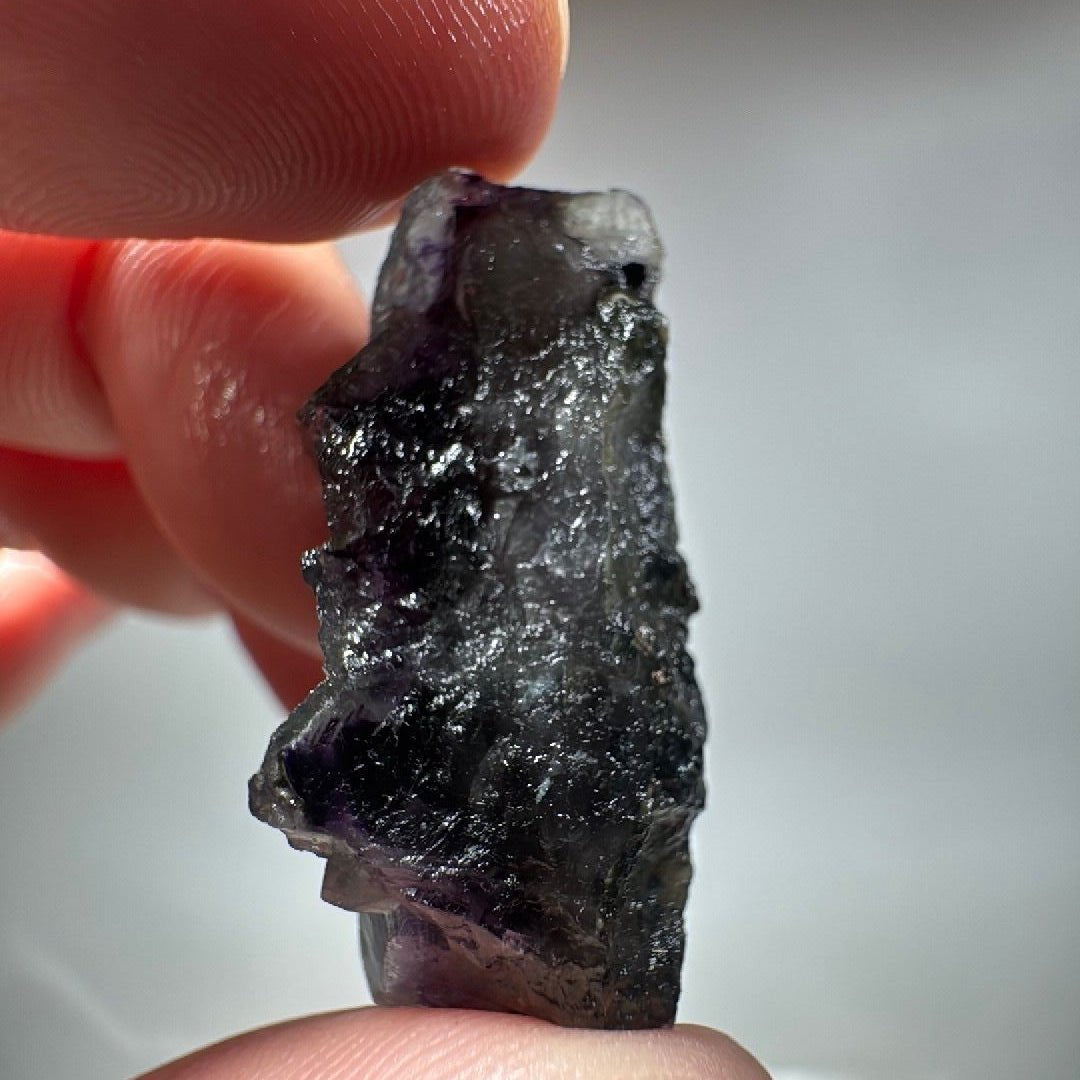The specimen turned on its side, deep violet cubes stacked along a grey-white matrix edge