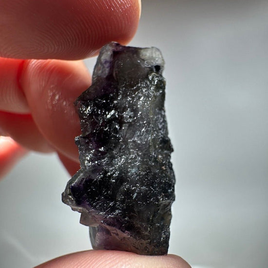 The specimen turned on its side, deep violet cubes stacked along a grey-white matrix edge