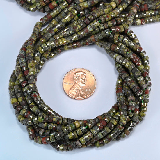 Dragon blood stone faceted heishi disc beads 2x4mm coiled in a loop around a US penny for scale, close-up of the faceted disc shape