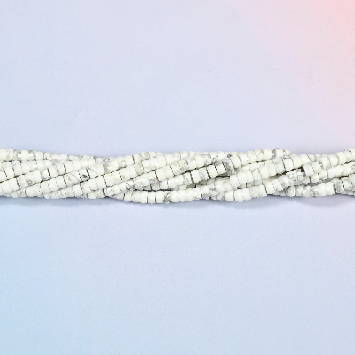 Strands of white howlite faceted heishi disc beads twisted together in a horizontal row