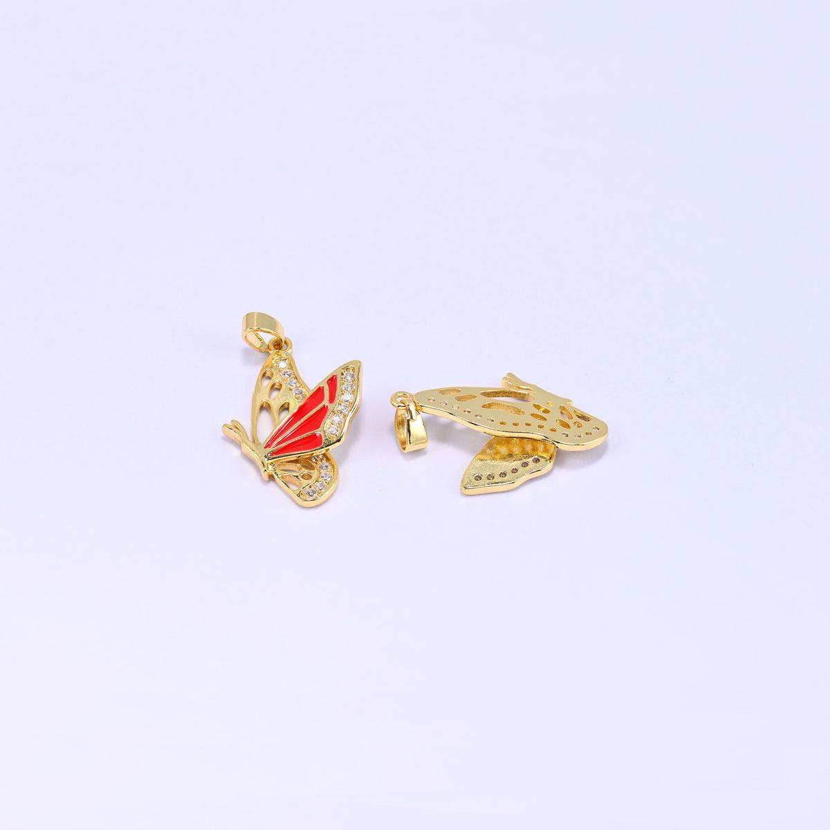 Flying butterfly charm pendant standing upright beside a second piece lying flat on its back, revealing the plain gold underside and cut out wing panels.