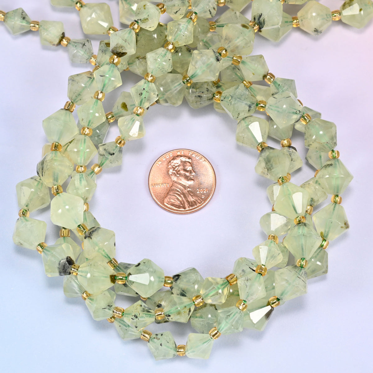 Close-up of Green Prehnite faceted bicone beads, 8mm and 10mm, coiled into a circle, highlighting the faceted shape and light green tone.