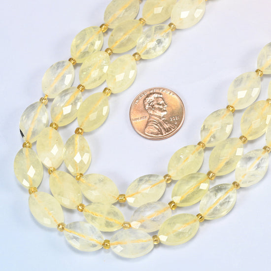 Close view of citrine faceted flat oval strands curving beside a US penny for scale
