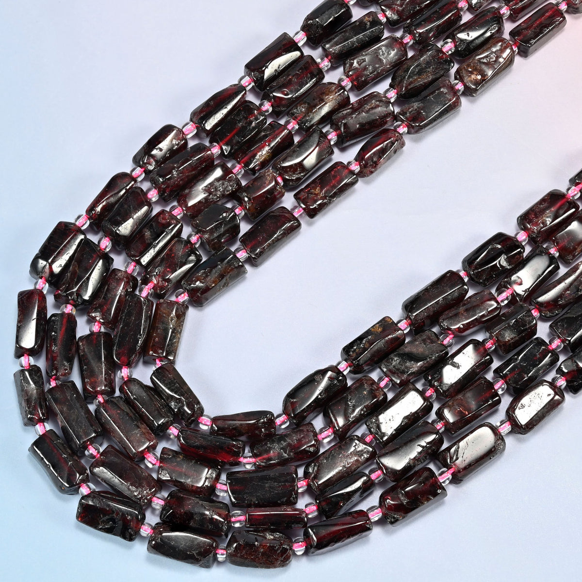 Red garnet tube beads in several strands curved into a wide U, glossy deep red garnet