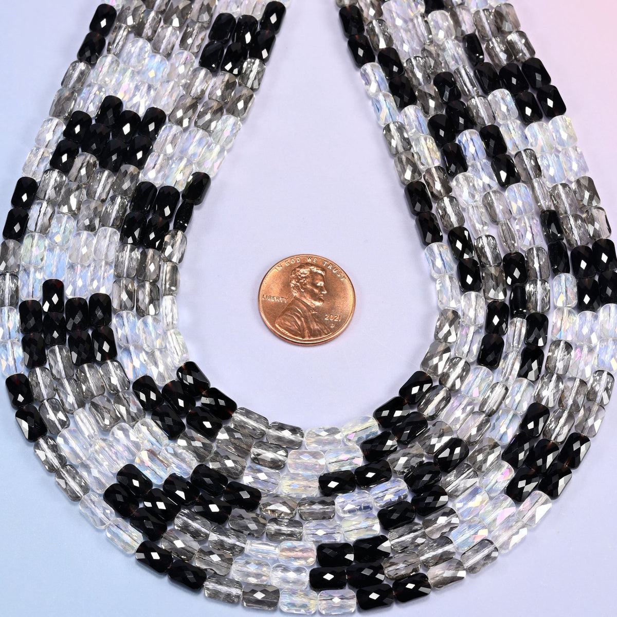 Black gray clear faceted rectangle glass beads ringed around a US penny set in the middle.