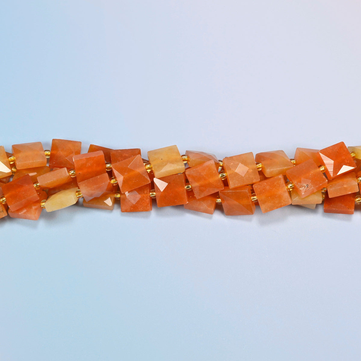 Strands of natural red aventurine faceted flat square beads twisted together in a horizontal row
