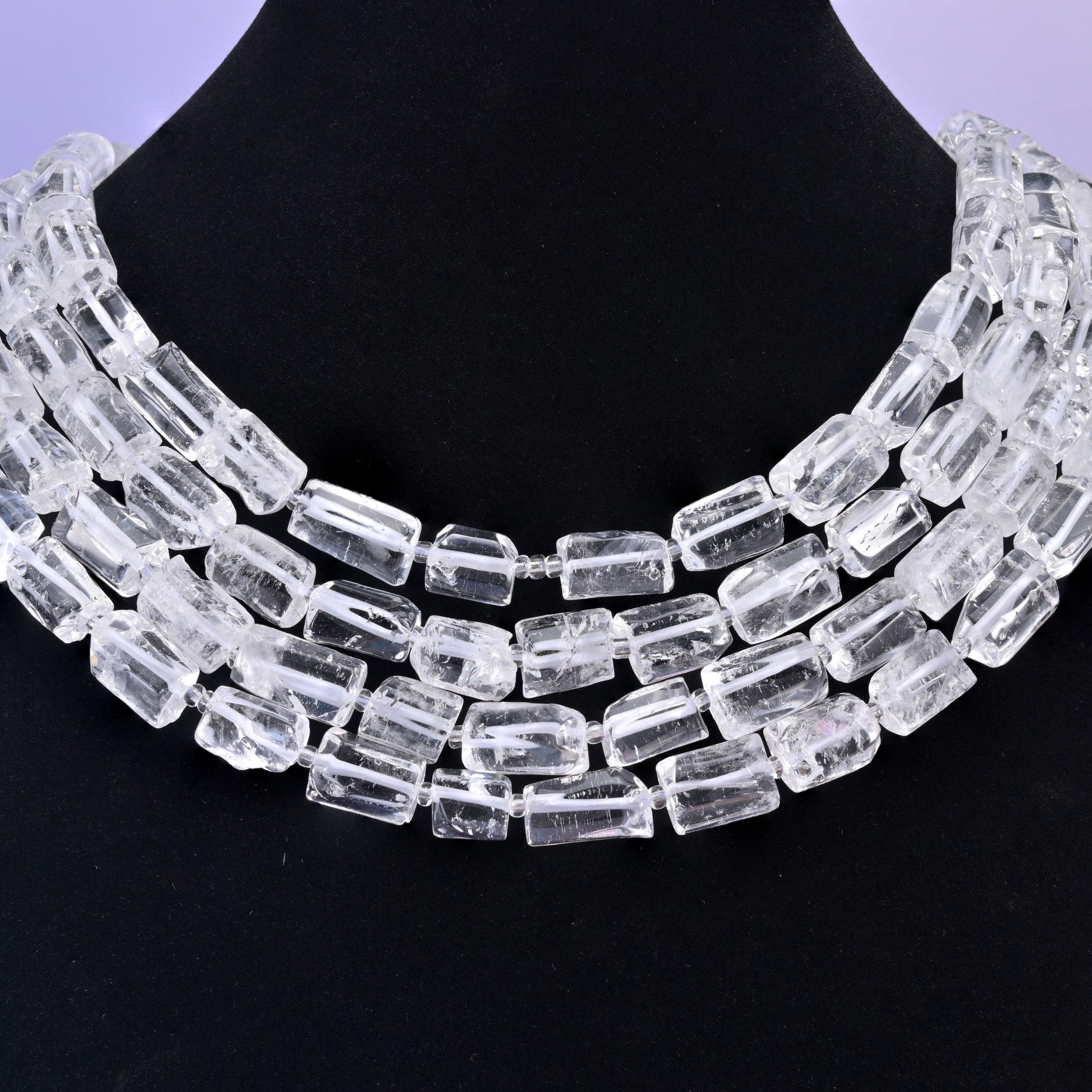 Displayed against a black neck form, the transparent tubes read as a bright three-row collar