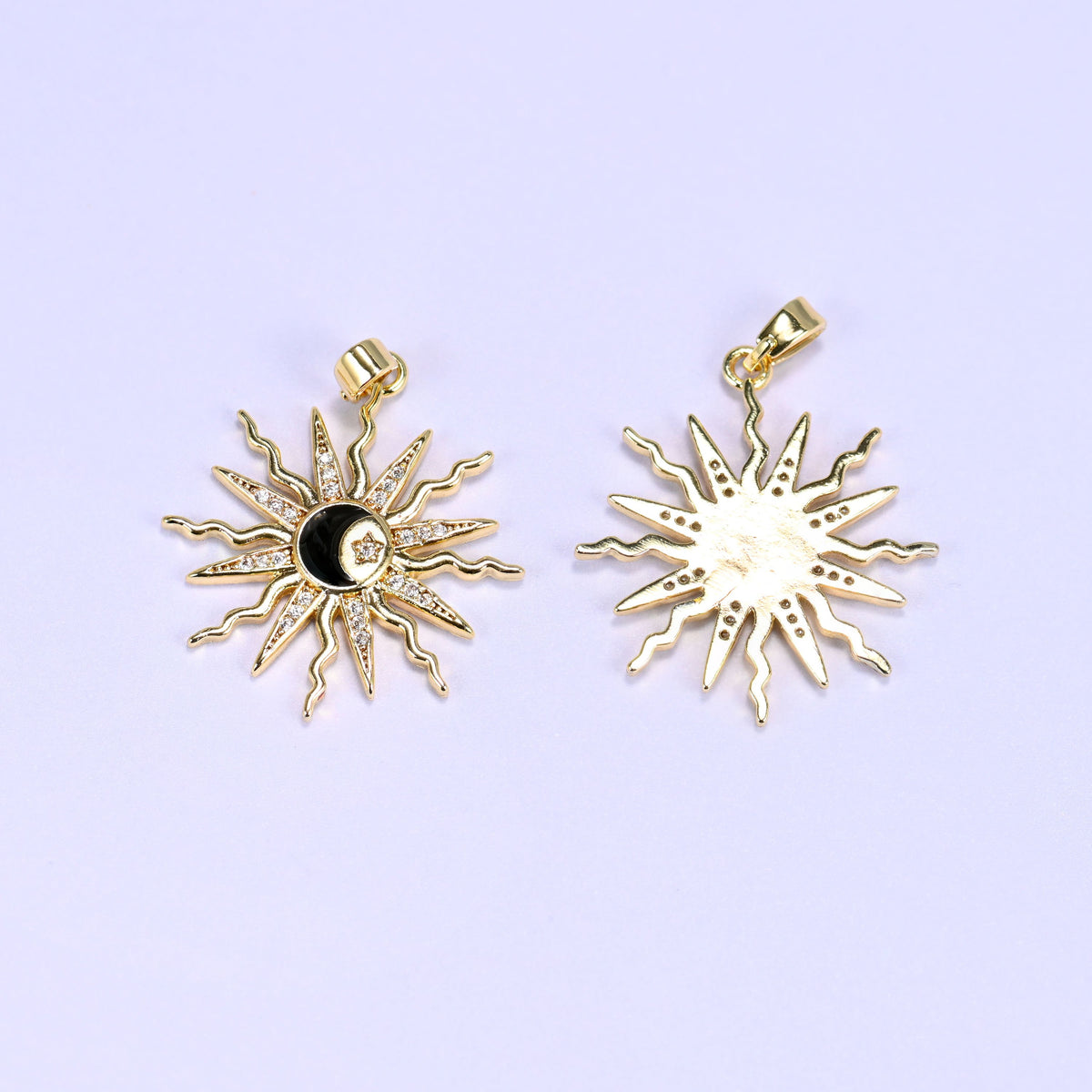 Black enamel moon sun zirconia charm beside a second pendant turned over, contrasting the paved face with the plain gold back.