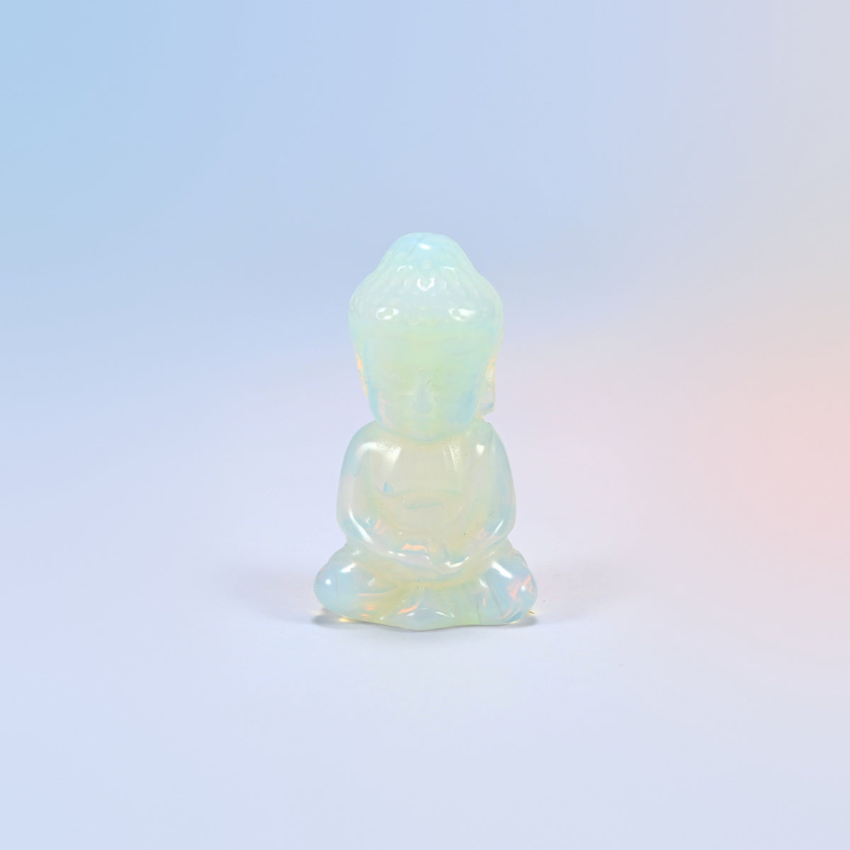 Opalite sitting Buddha carving with a milky glow and a soft blue sheen, man-made glass
