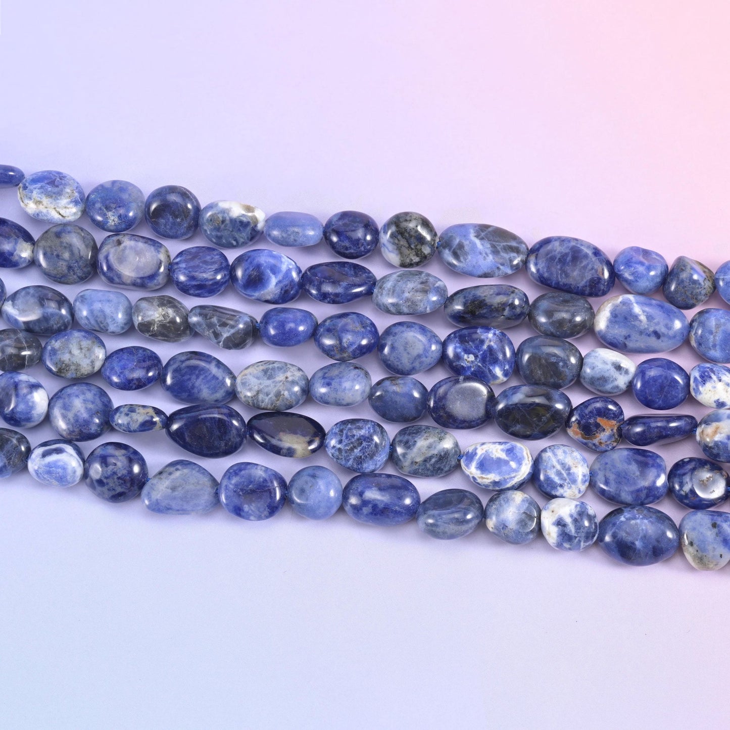 Rows of blue Sodalite nuggets showing white marbling and varied pebble sizes