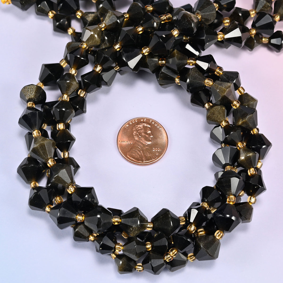 Gold obsidian bicone beads coiled into a round ring, 8mm and 10mm sizes available, gold-tone spacers throughout.