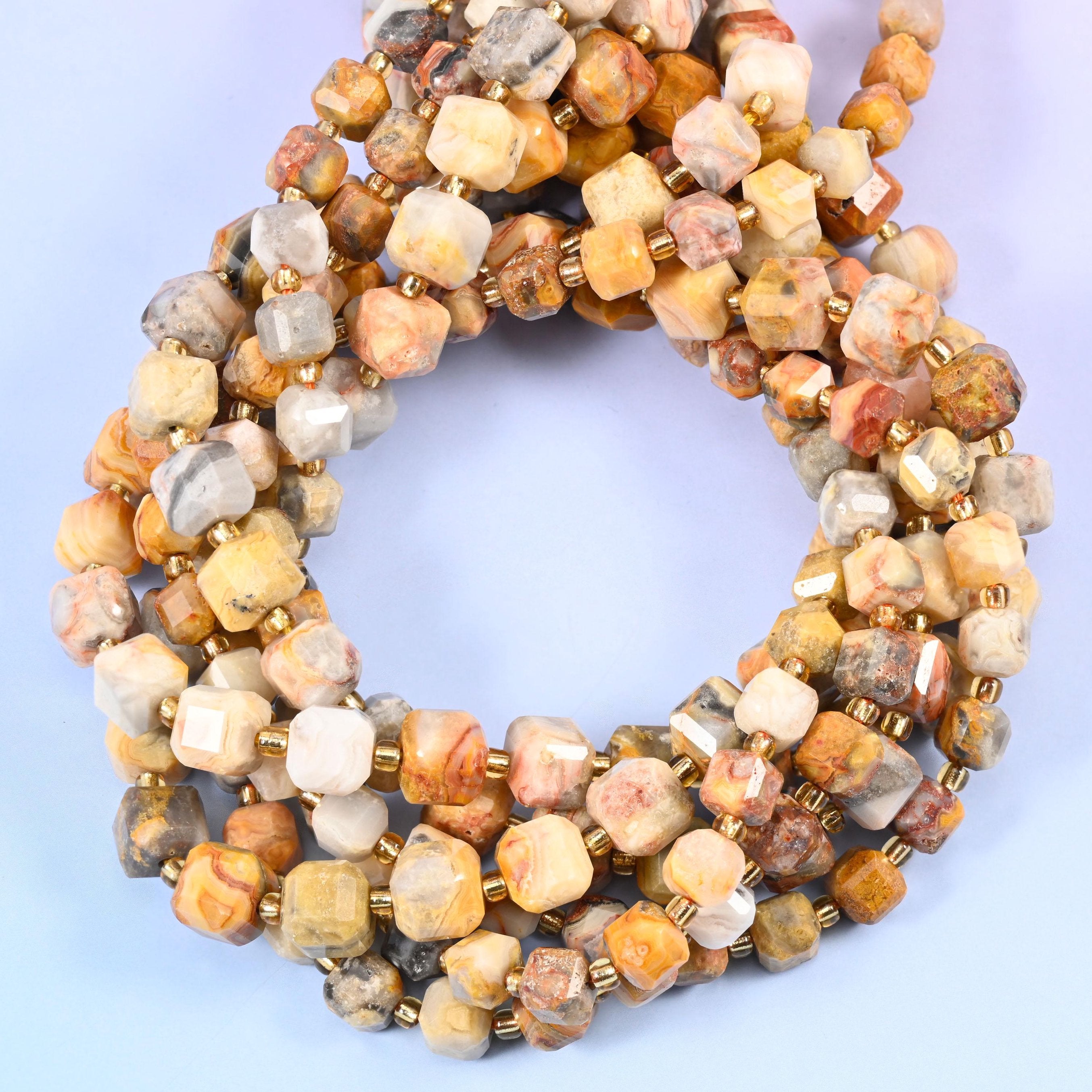 Warm sandy beige and cream cubes banded with apricot, rust and soft grey, every face cut flat so the polished stone catches light from a different angle.