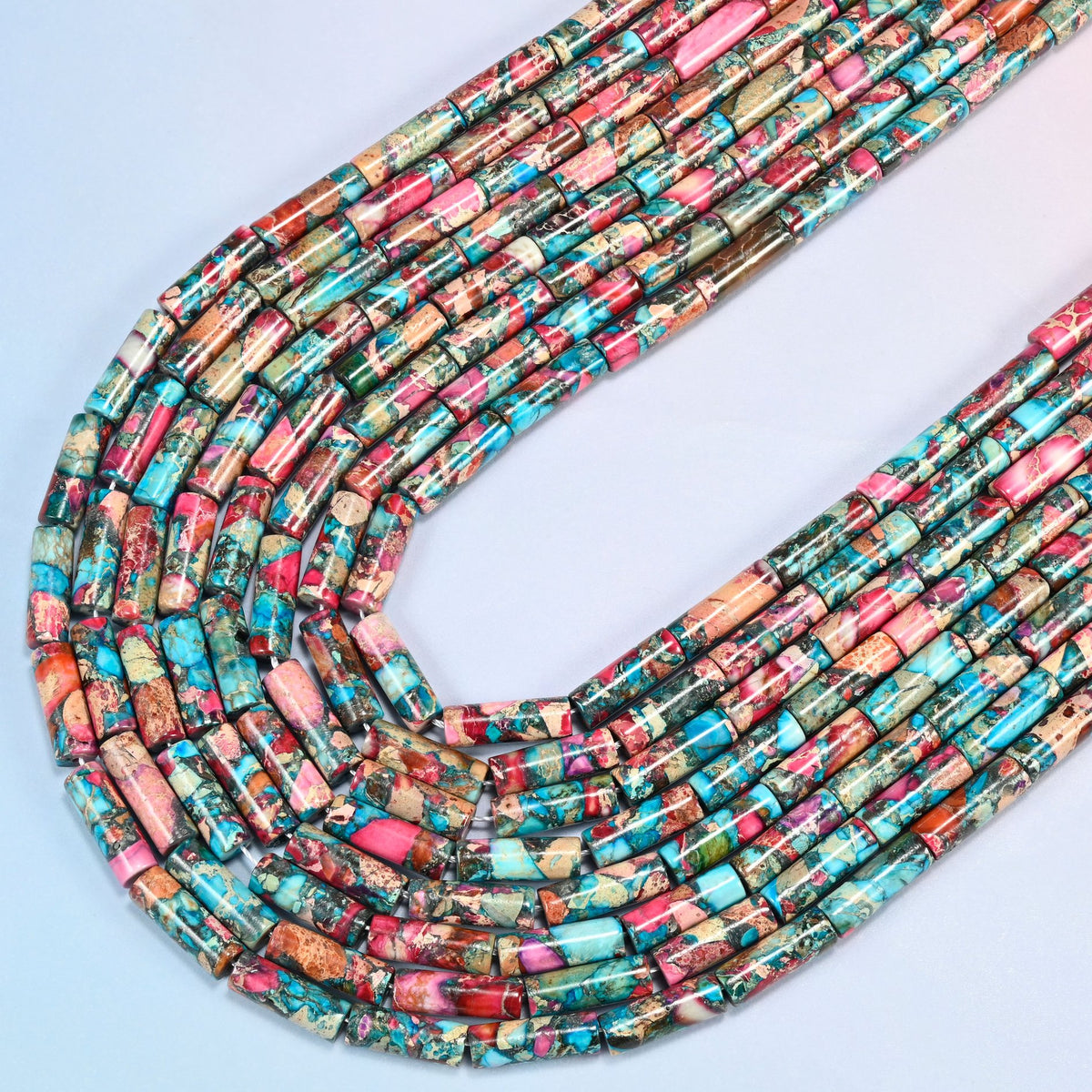 Dyed sea sediment jasper tube beads 13x4mm in several strands curved into a wide U, turquoise, pink and peach marbled tubes