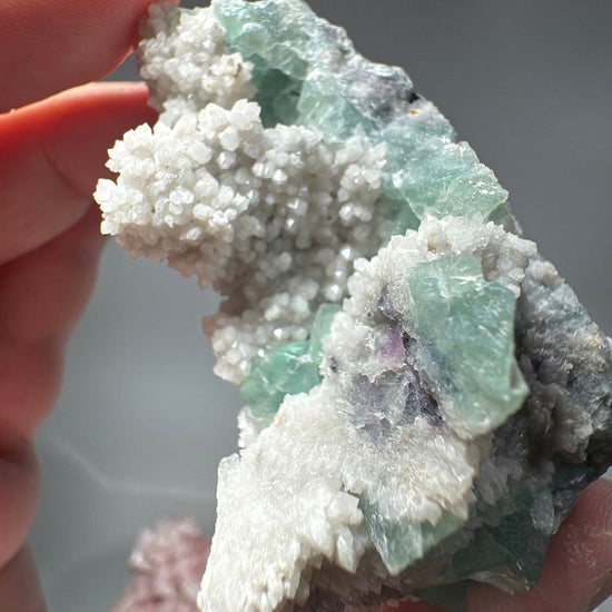 Angled view where green fluorite and white quartz meet along a dark violet seam