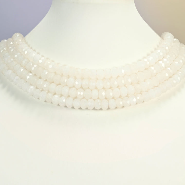 White jade faceted rondelle strands arranged as a layered collar on a white display bust, milky white beads across the neck