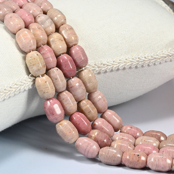 Pink Rhodonite faceted barrel drum beads draped in a soft curve, dusty rose banded with cream and light tan