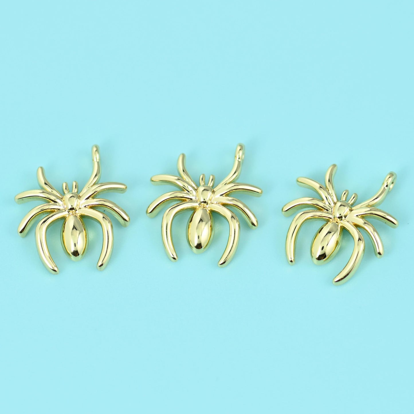 A slim polished spider with eight splayed legs and a smooth rounded abdomen, cast in brass with a bright 18K gold fill and…