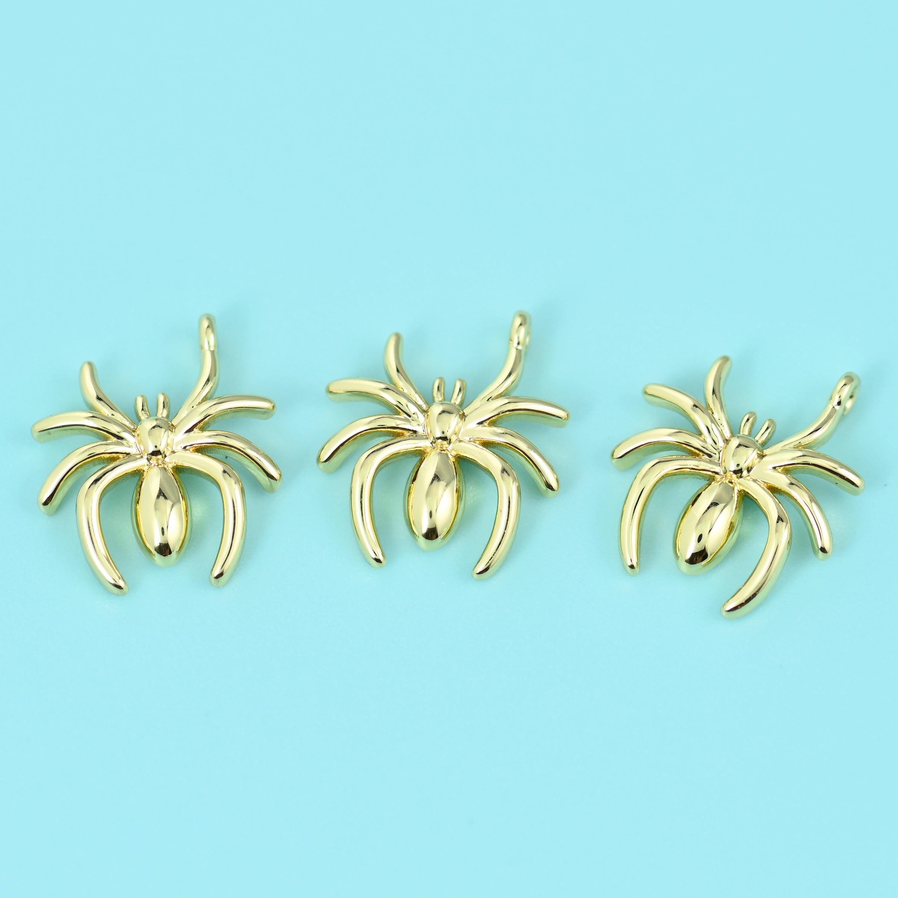 A slim polished spider with eight splayed legs and a smooth rounded abdomen, cast in brass with a bright 18K gold fill and…