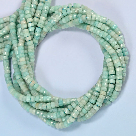 Green amazonite faceted heishi disc beads coiled into overlapping loops, whole strands of soft light green stone