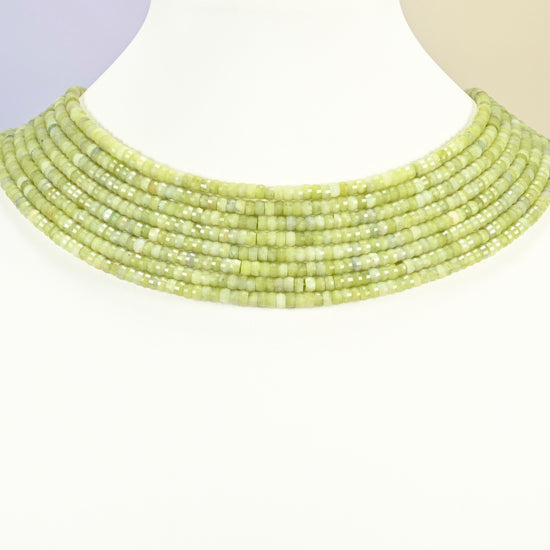 South Jade faceted heishi disc strands arranged as a layered collar on a white display bust, light green beads across the neck